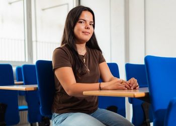 Dates de rentrée 2025/2026 Jeune femme brune assise dans une salle de classe regarde la caméra