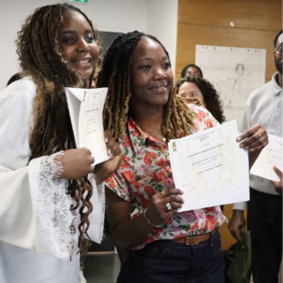 2 étudiantes debout souriant et montrant leur diplôme