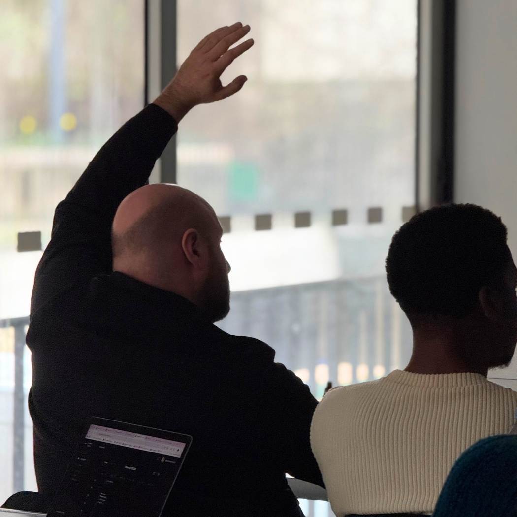 Etudiant de dos en classe avec un pull noir lève la main